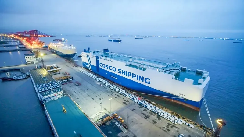 A car carrier ship at a port with export vehicles lined up on the quay